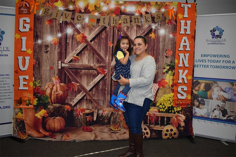 Mother holding her young daughter at the Thanksgiving giveaway