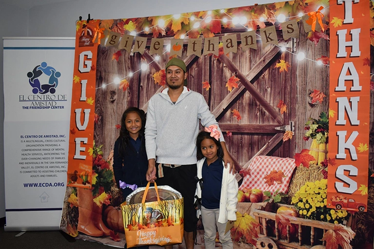 Father with his two daughters and a Thanksgiving food bag